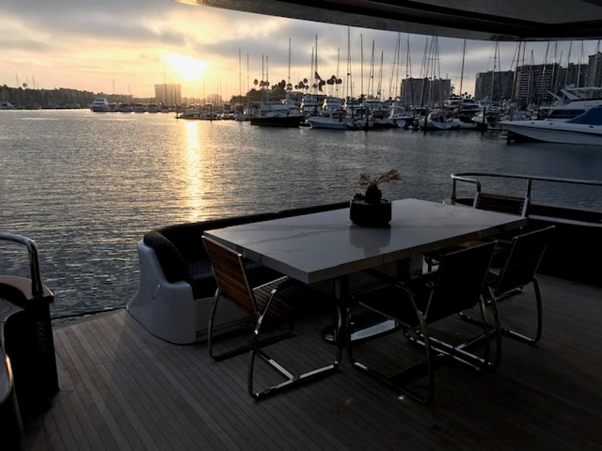 a table with chairs on a deck overlooking a harbor with boats aboard KISSES Yacht for Sale