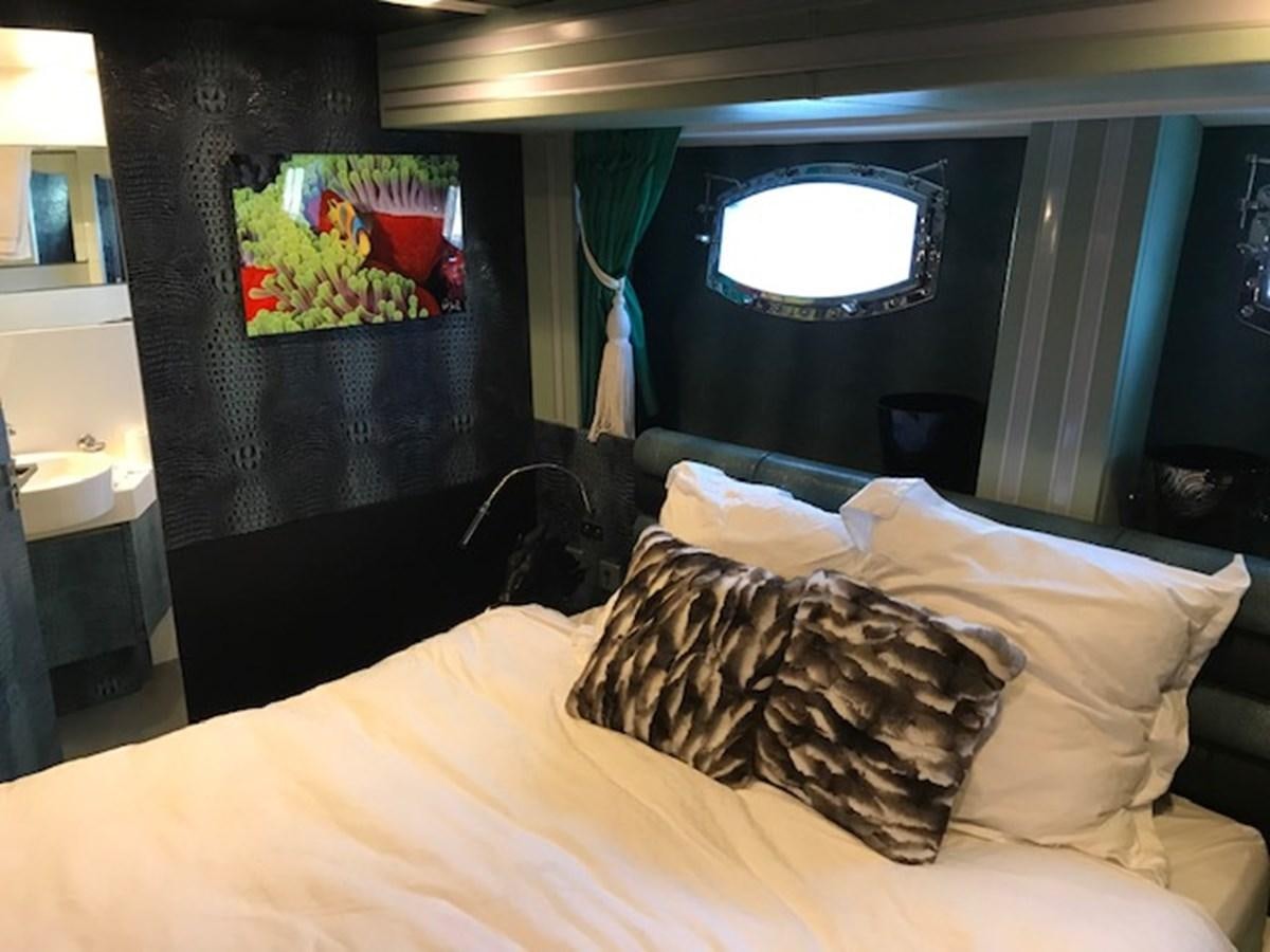 a bed with a television on the wall aboard KISSES Yacht for Sale