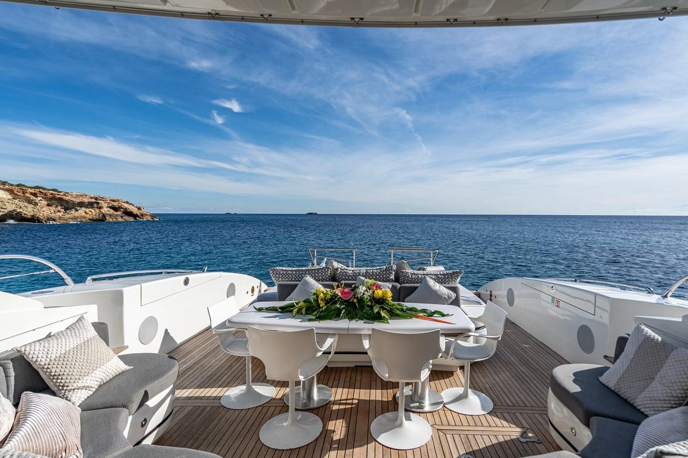 a table with chairs and a view of the ocean aboard FIVE STARS Yacht for Sale
