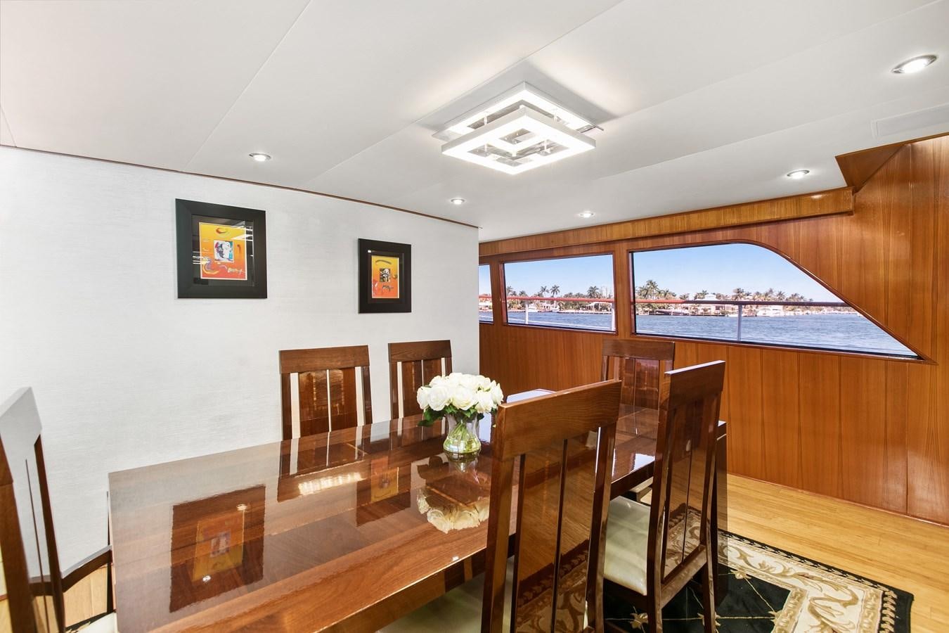 a dining table and chairs in a room with a large window aboard TRES HERMANOS VI Yacht for Sale