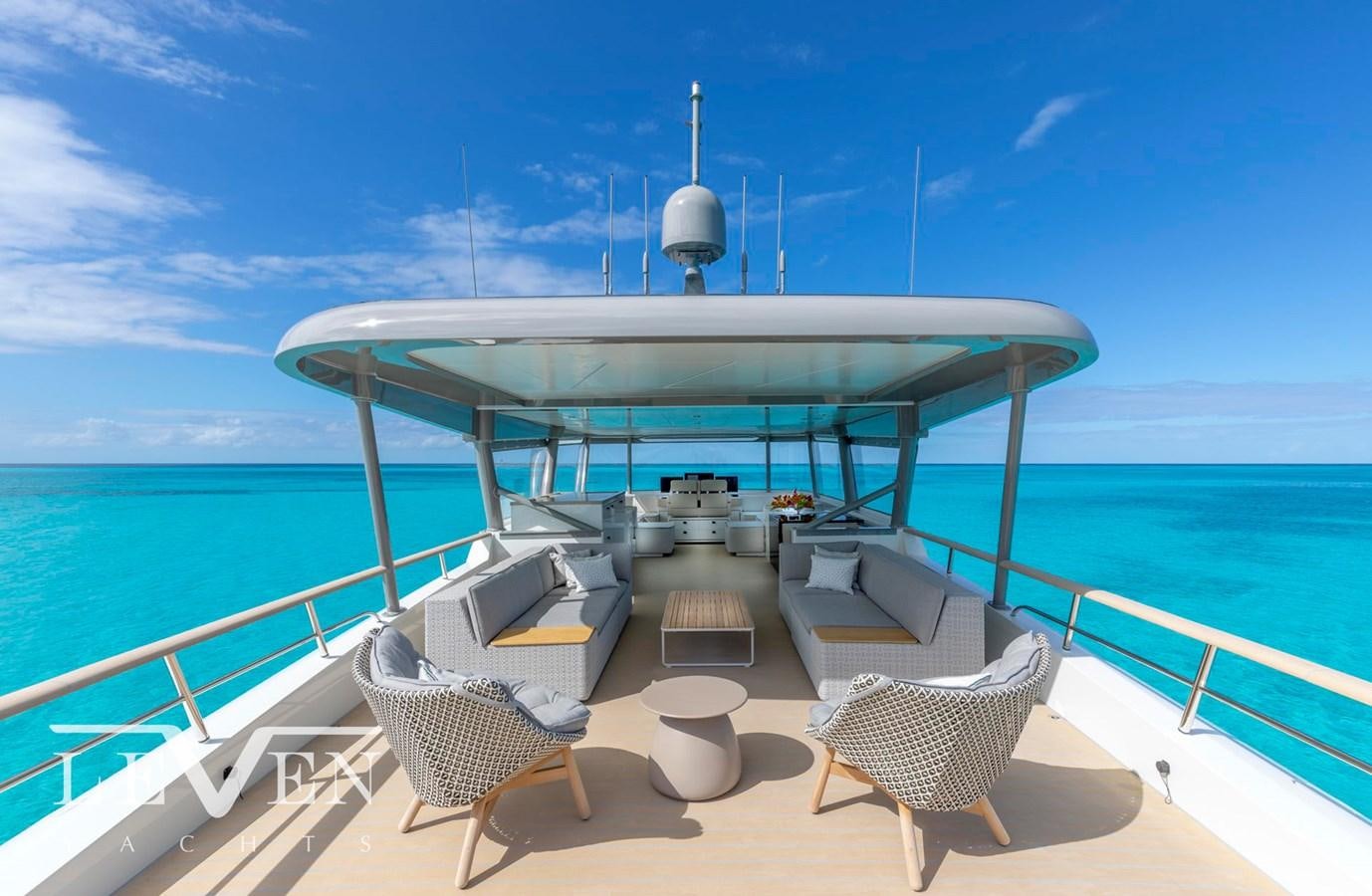 a deck with chairs and a table on it aboard LEVEN 90 Yacht for Sale