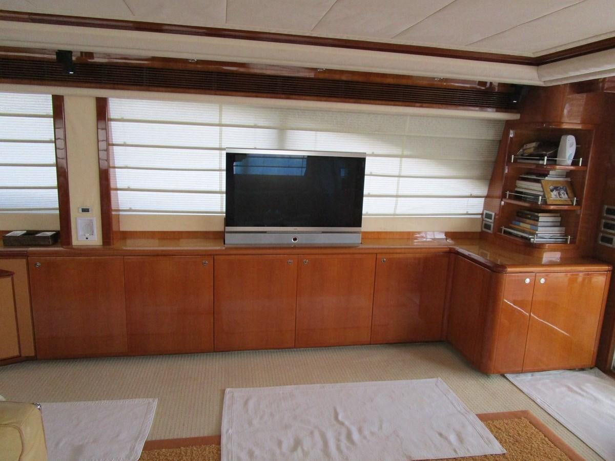 a room with a tv and a shelf with books aboard NACL Yacht for Sale