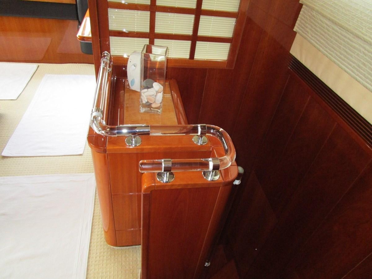 a wooden cabinet with a glass and a bottle of wine aboard NACL Yacht for Sale