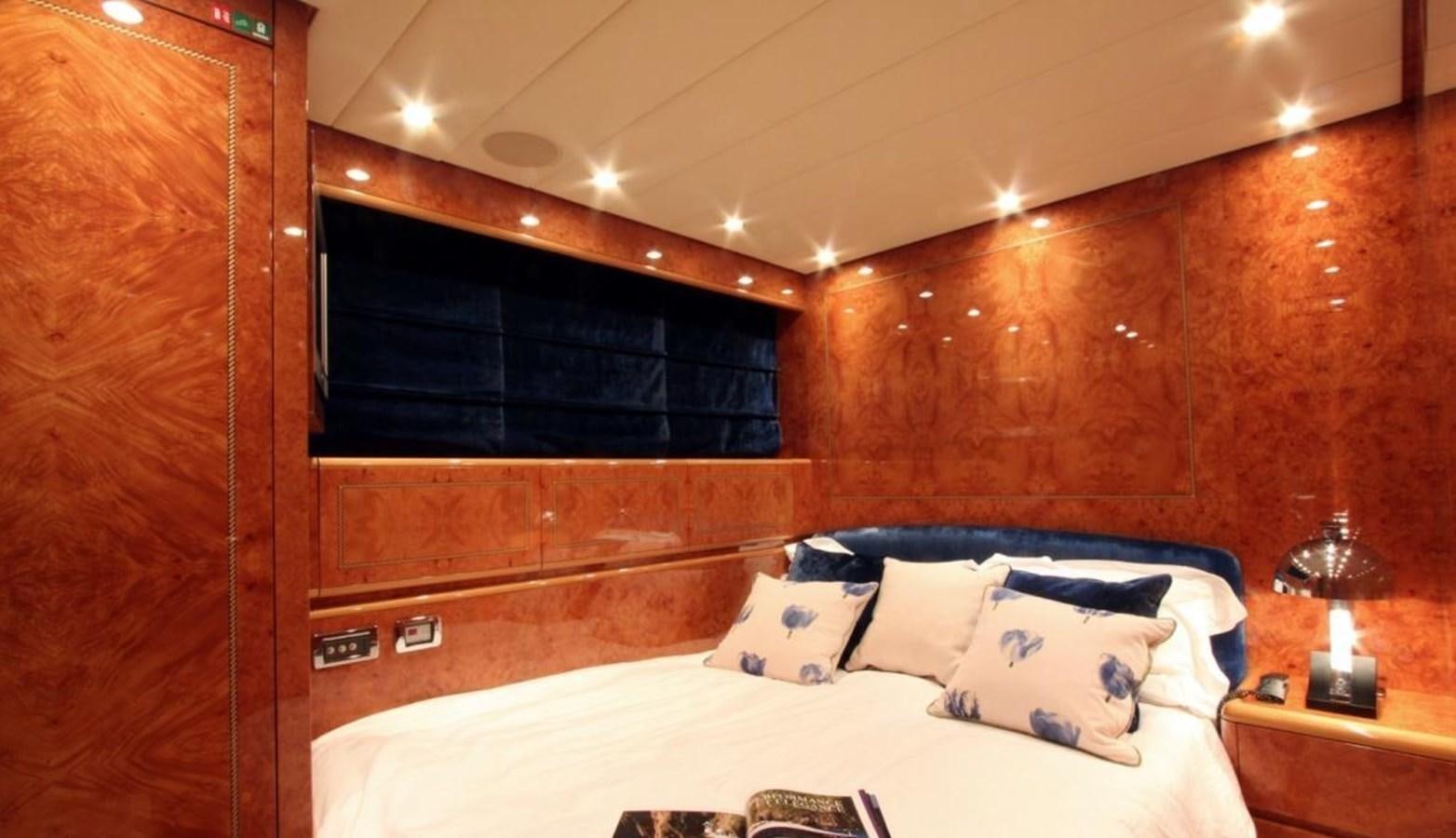 a bed with a white sheet and pillows in a room with wood walls aboard MAGENTA I Yacht for Sale