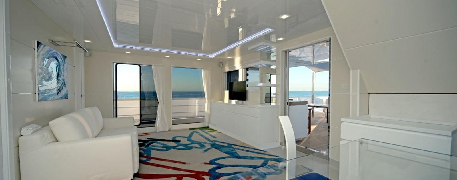a room with a blue rug and white furniture aboard OCEAN KING 88 Yacht for Sale