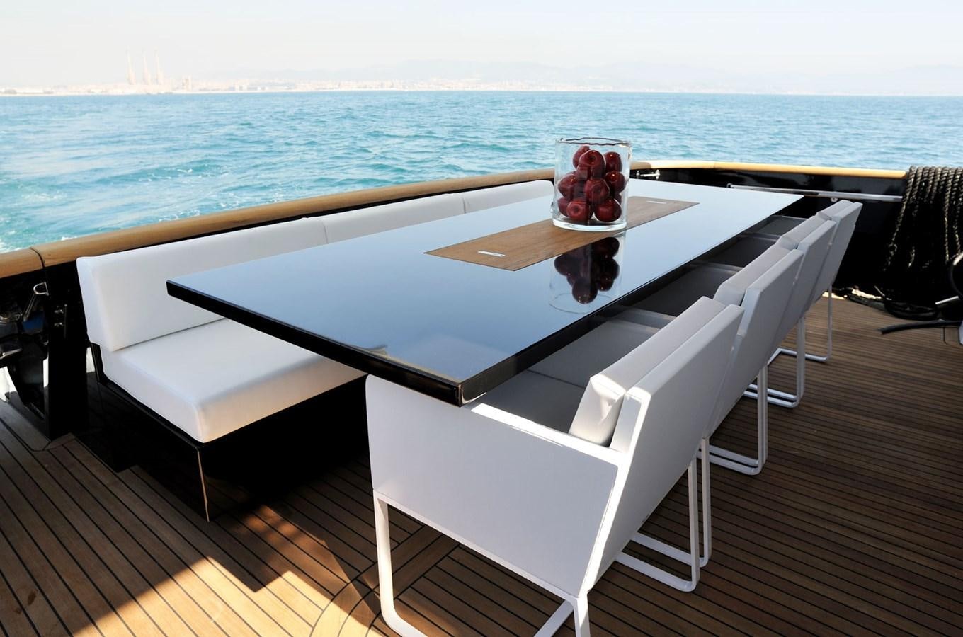 a white table with a white chair on a deck overlooking the ocean aboard PETARDO C Yacht for Sale