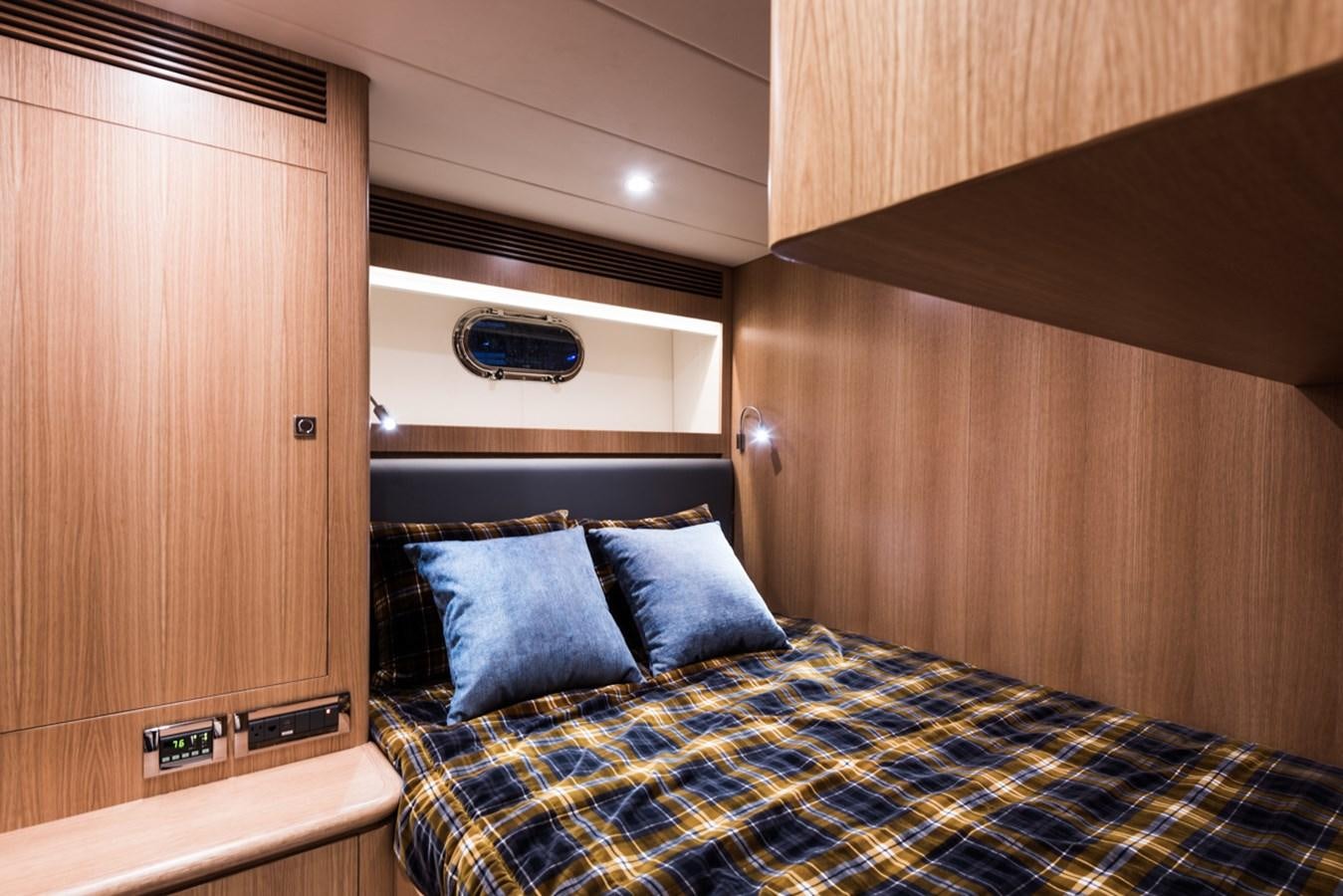 a bed with a blue and white comforter and a wood cabinet aboard E84 (NEW BOAT SPEC)  Yacht for Sale