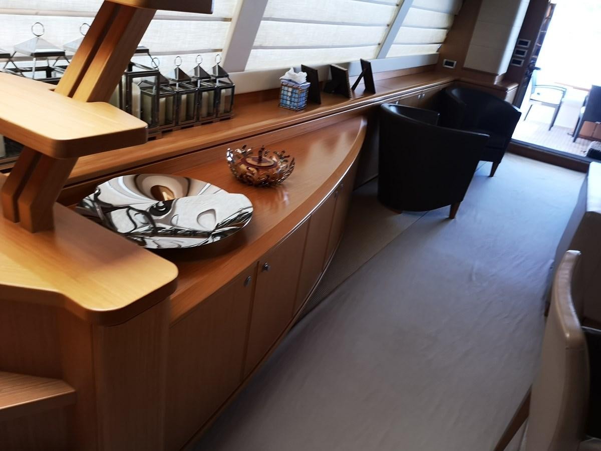 a table with a bottle and a chair in a room with chairs aboard RICACHA 2012 FERRETTI 830 @ ACAPULCO Yacht for Sale