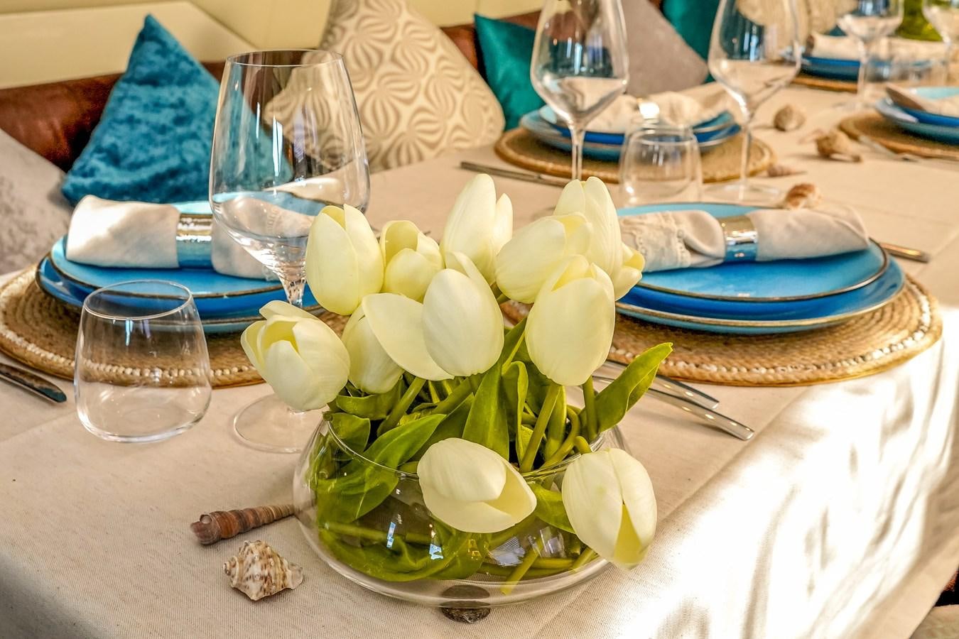 a table with plates and glasses aboard MILU II Yacht for Sale