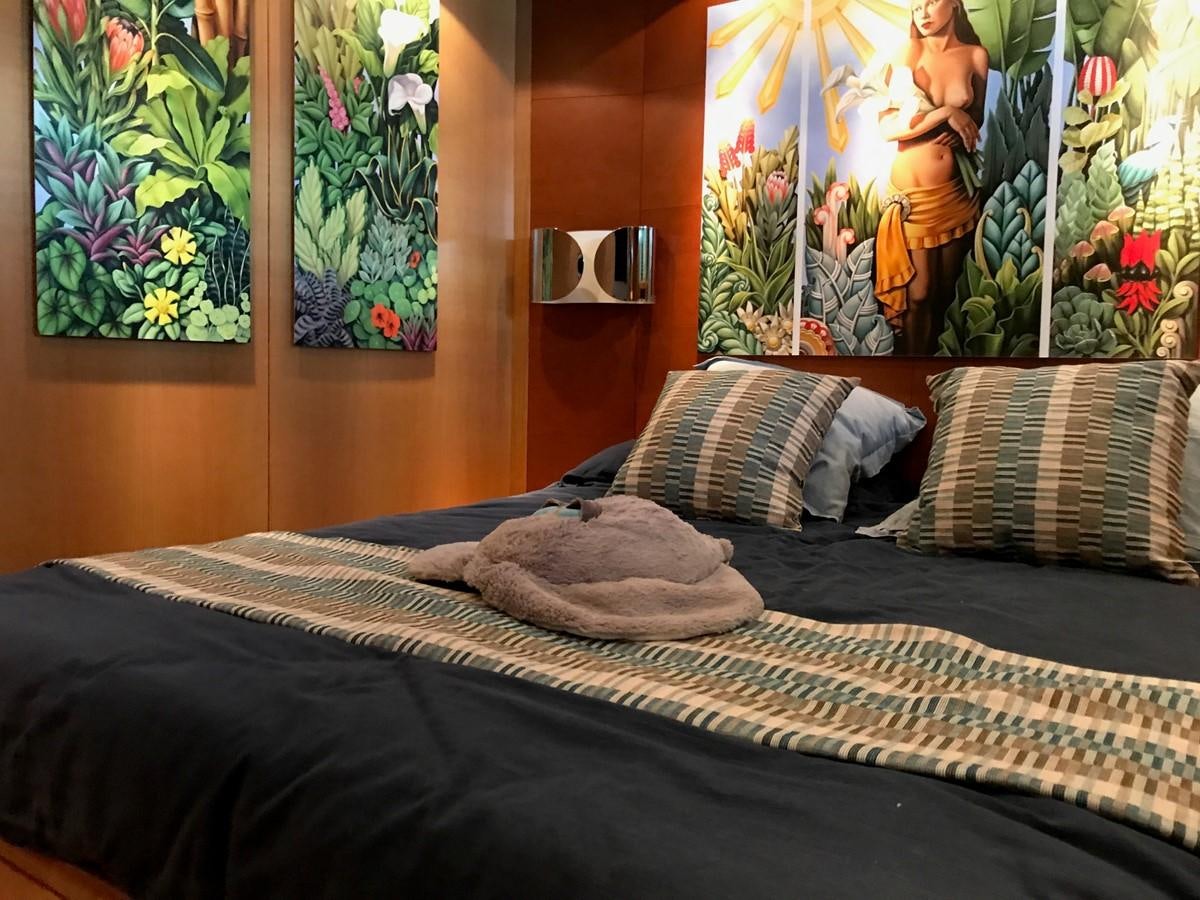 a bed with a black comforter and colorful art on the wall aboard LADY LO OF LONDON Yacht for Sale