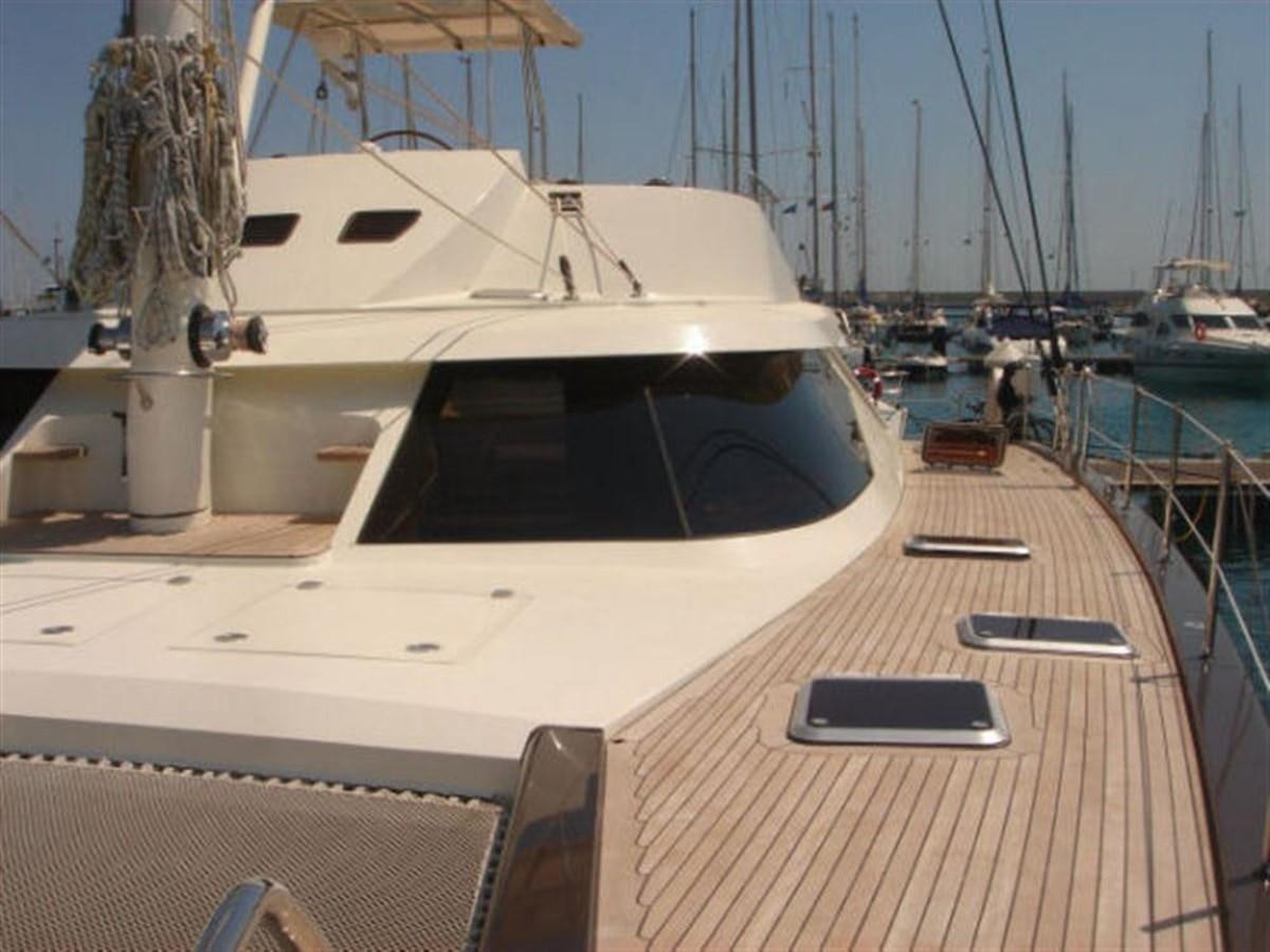 a deck with a laptop on it and boats in the background aboard 75' 2008 YAPLUKA LUXURY CATAMARAN Yacht for Sale