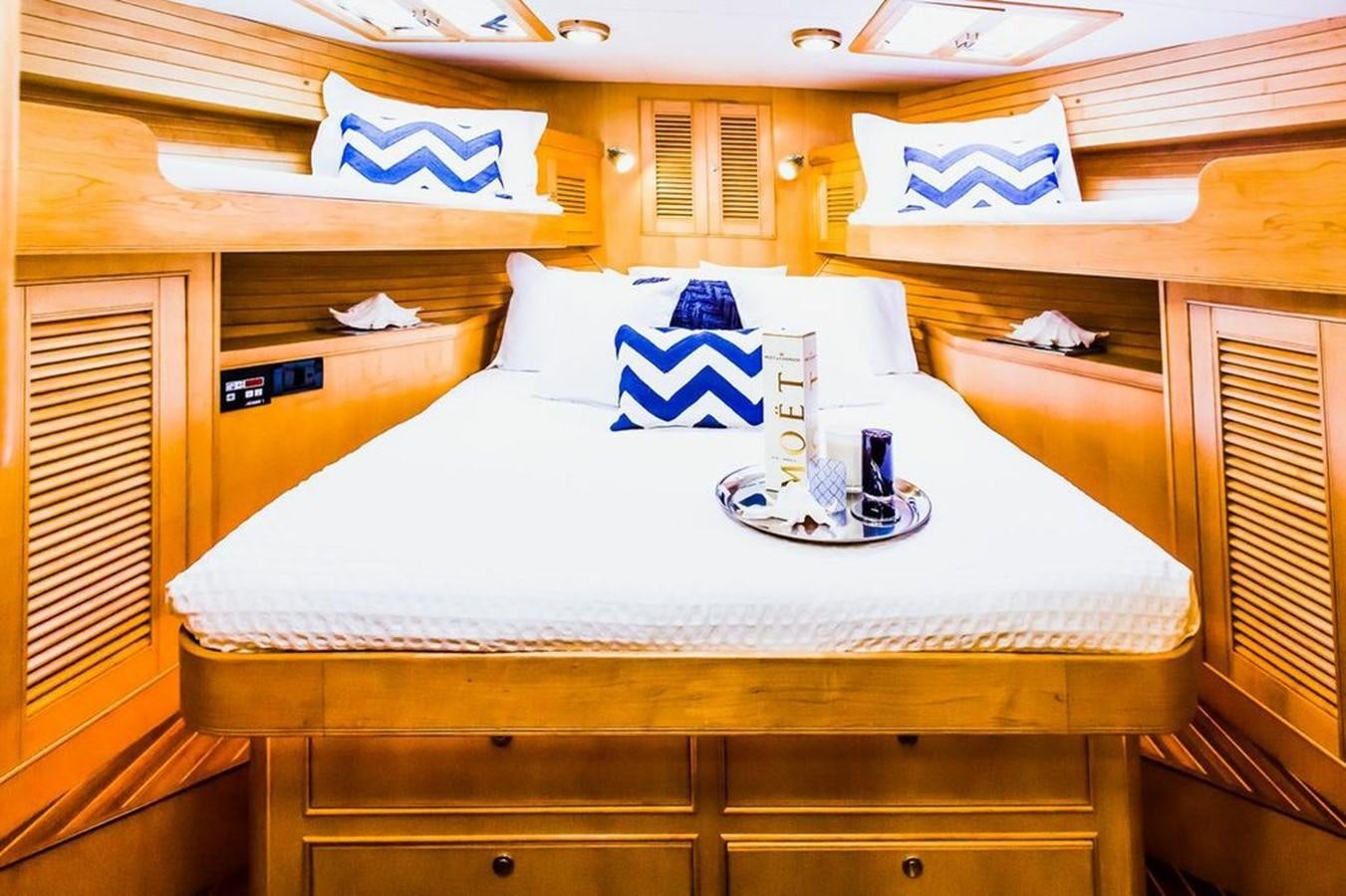 a bed with a white sheet and blue and white striped pillows aboard 72' MARLOW RAISED PILOTHOUSE MOTOR YACHT EXPLORER I Yacht for Sale
