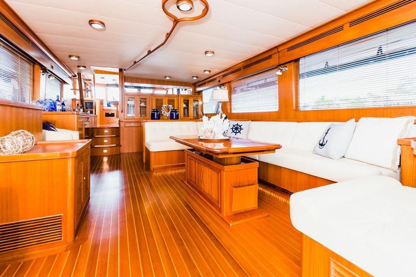 a room with a wood floor and a table with a couch and a window with a wood floor aboard 72' MARLOW RAISED PILOTHOUSE MOTOR YACHT EXPLORER I Yacht for Sale