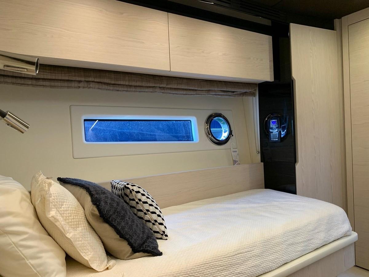 a bed with a white sheet and a blue screen on the wall aboard AMALFI Yacht for Sale