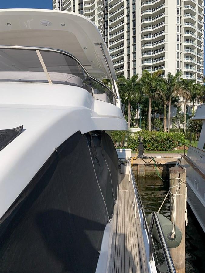 a white car with a black hood parked on a street with tall buildings aboard AMALFI Yacht for Sale