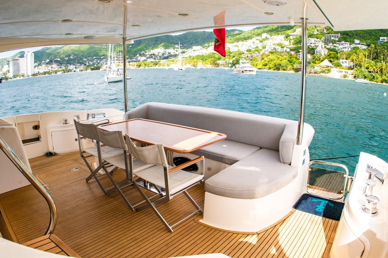 a room with a table chairs and a flag on the balcony aboard VA BENE 2011 AZIMUT 70 FLY Yacht for Sale