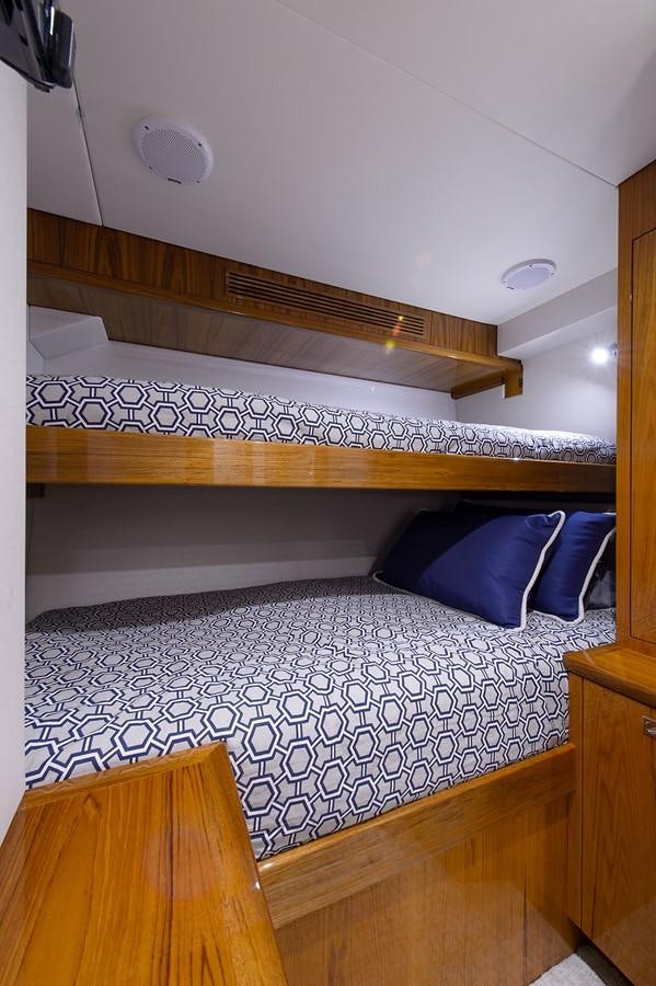 a bed with a blue and white comforter and a wooden headboard aboard NOTORIOUS Yacht for Sale