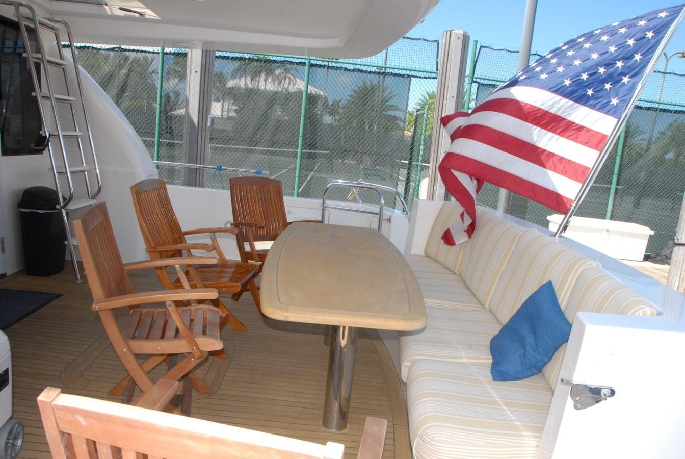 a deck with a flag and tables aboard ROOM SERVICE Yacht for Sale