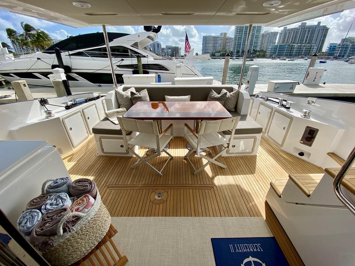 a room with a couch and a table with chairs and a large city landscape aboard SEARENITY II Yacht for Sale