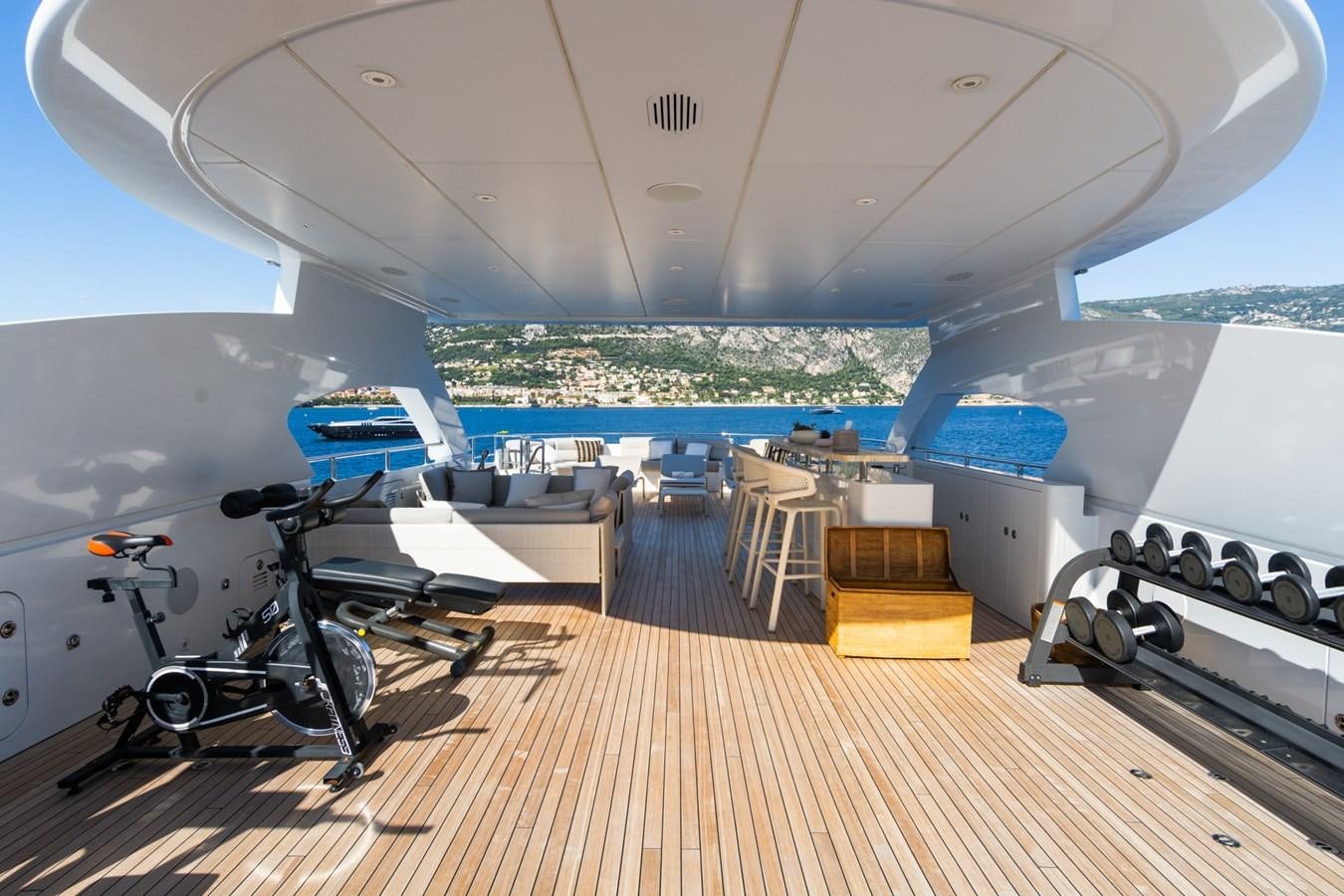 a room with a table chairs and a bike on a deck aboard MY SECRET Yacht for Sale