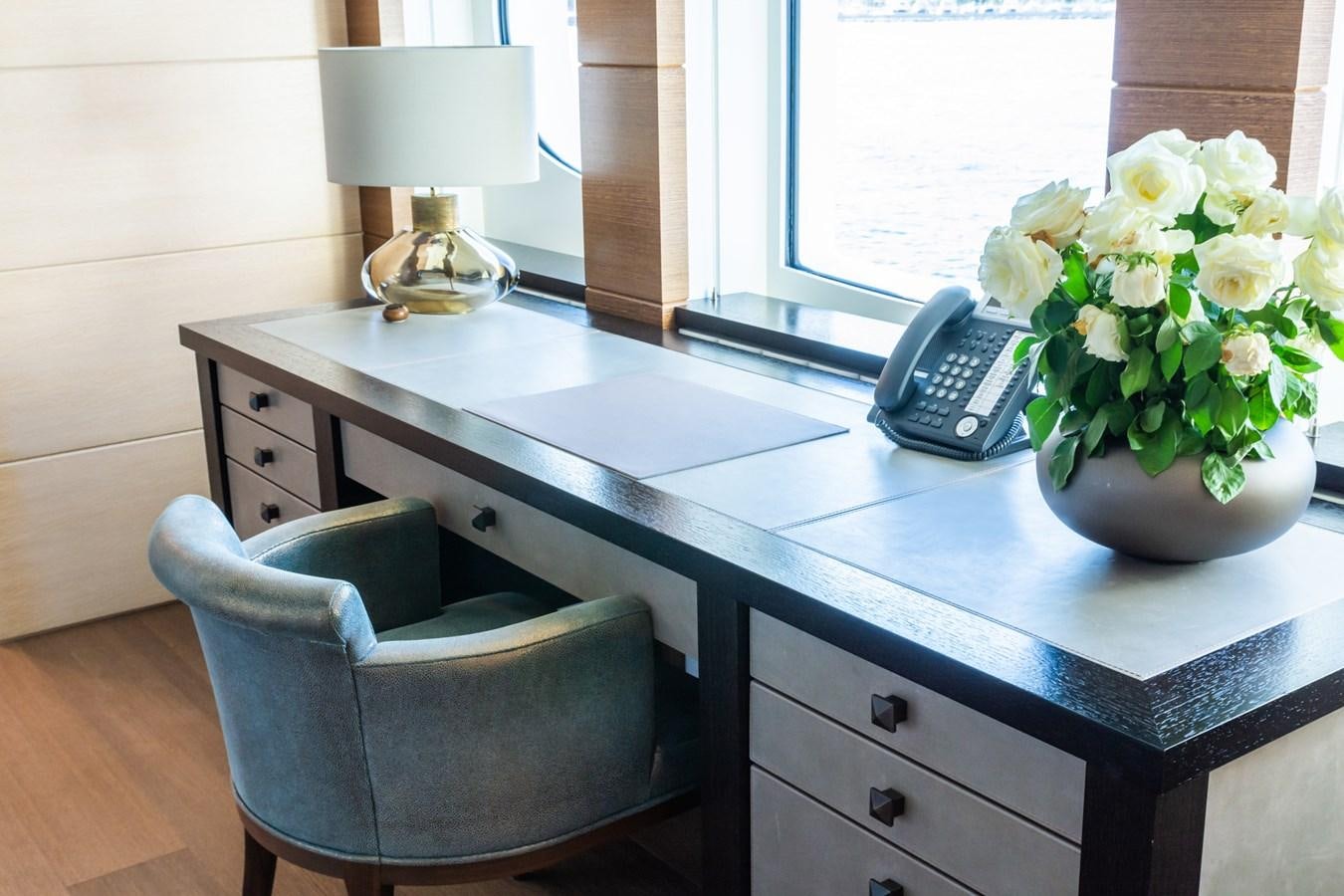 a desk with a chair and a vase of flowers on it aboard MY SECRET Yacht for Sale