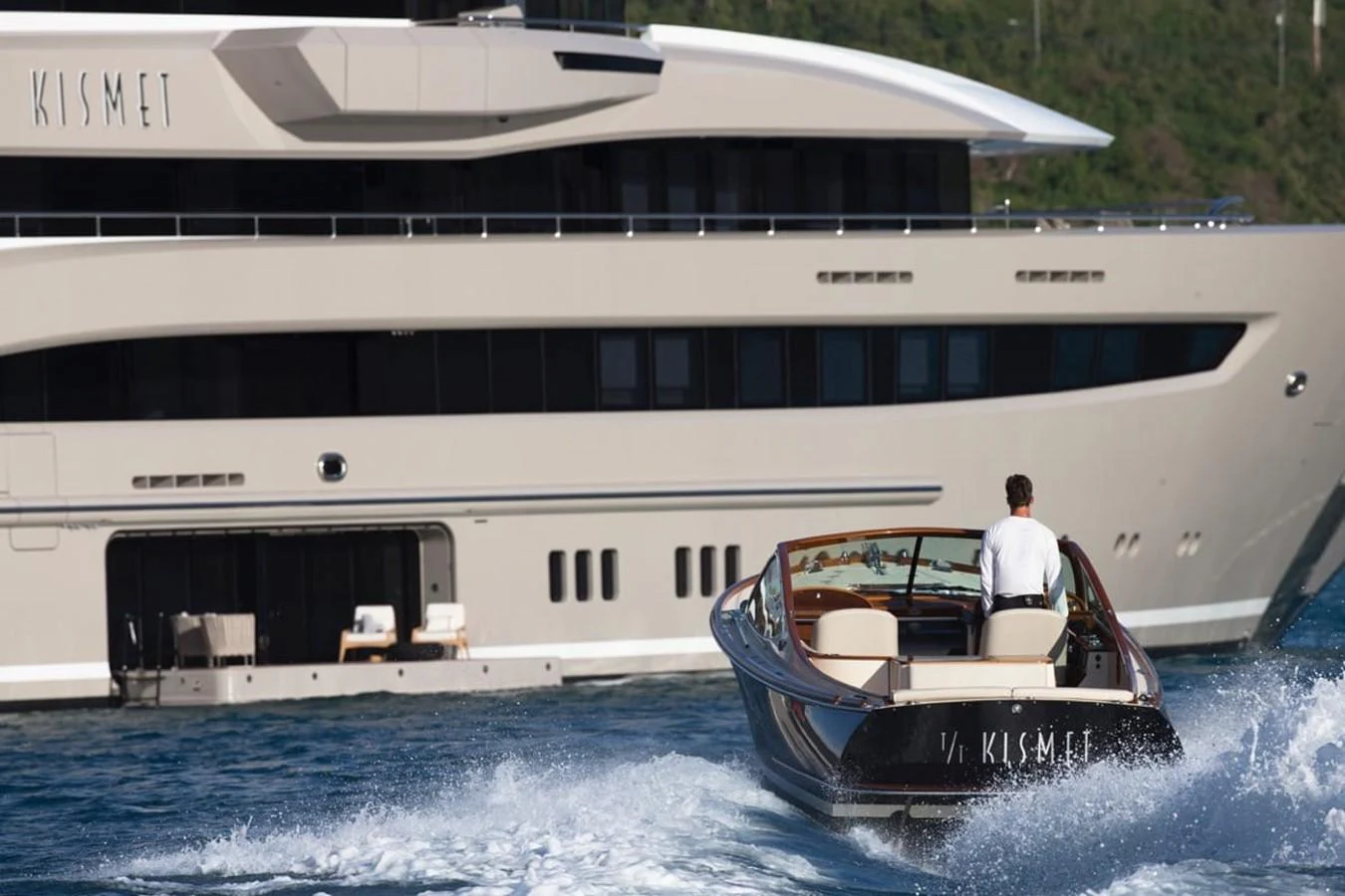 a person on a boat in the water next to a large boat aboard WHISPER Yacht for Charter