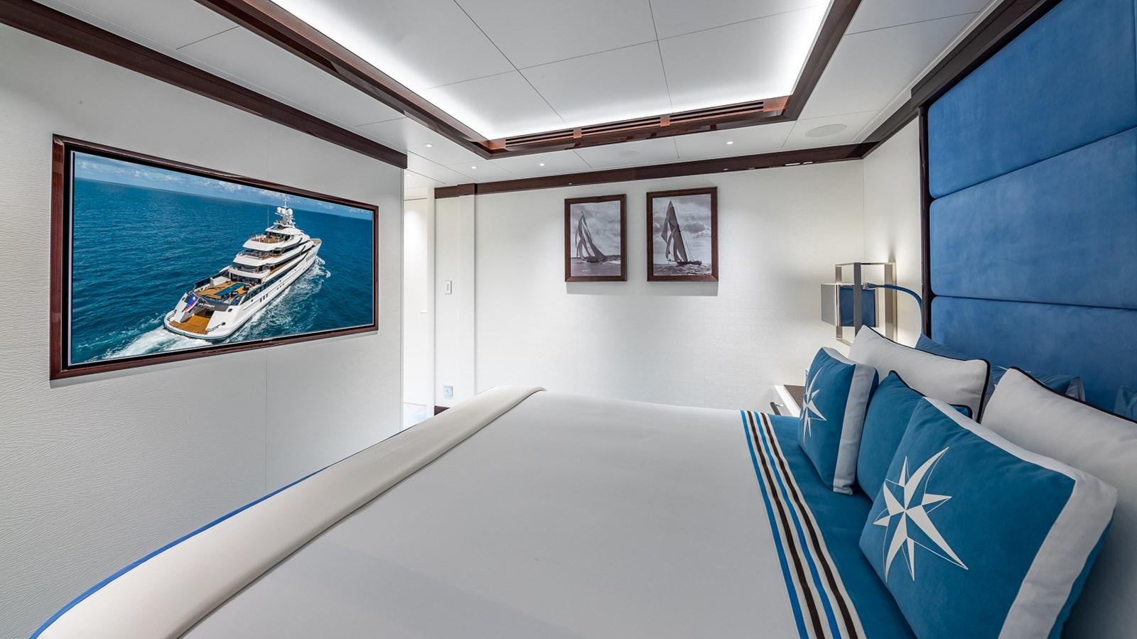 a room with a blue couch and a television on the wall aboard CC-SUMMER Yacht for Sale
