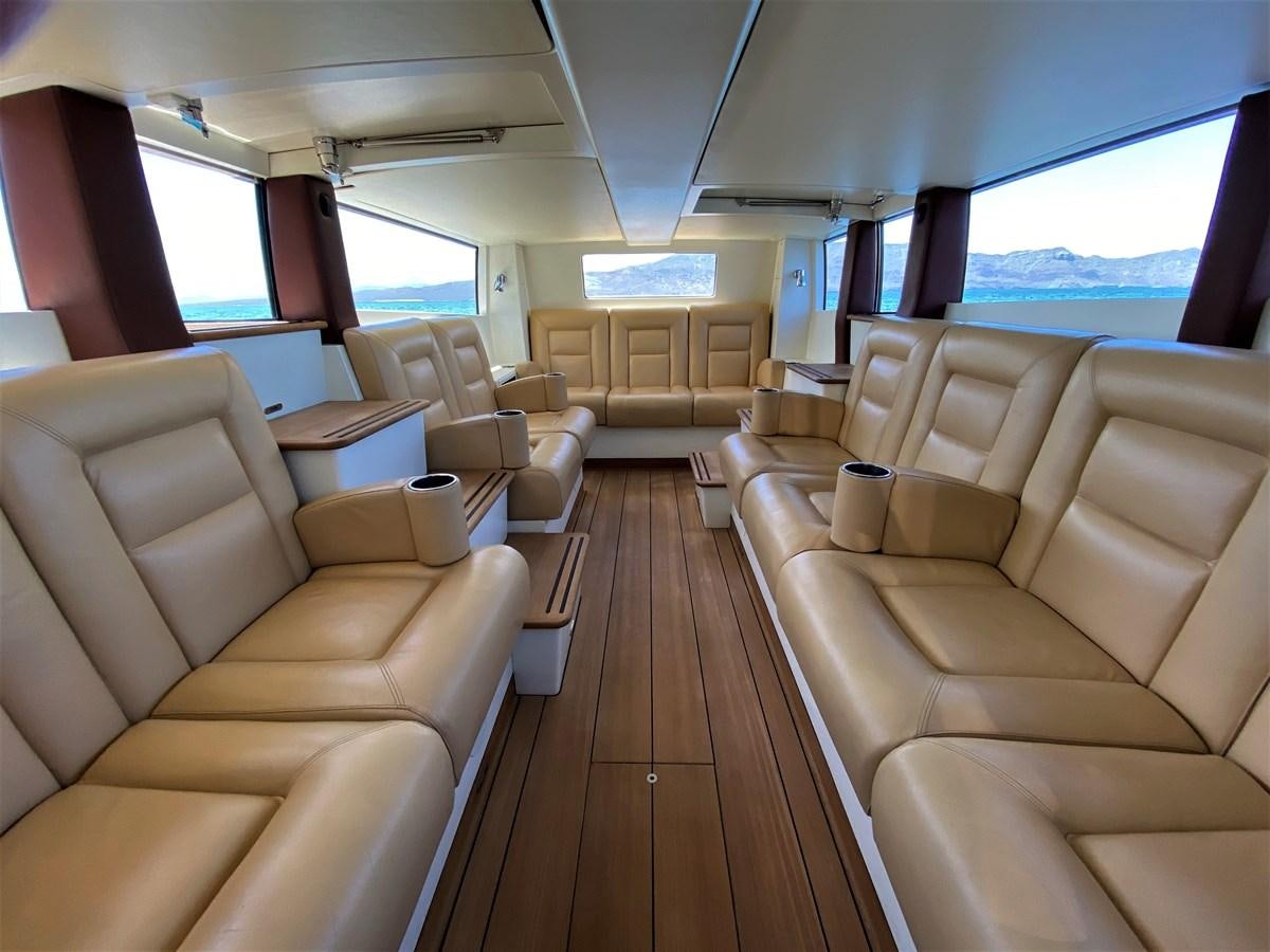 a room with a wood floor and a large window with chairs and a wood floor aboard MAN OF STEEL Yacht for Sale