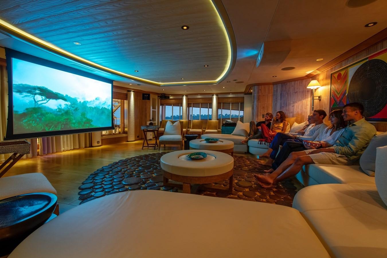 a group of people sitting in a room watching a large screen aboard SUNRAYS Yacht for Sale