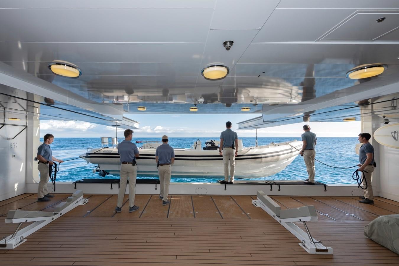 a group of people standing on a deck looking at a boat aboard EYE Yacht for Sale