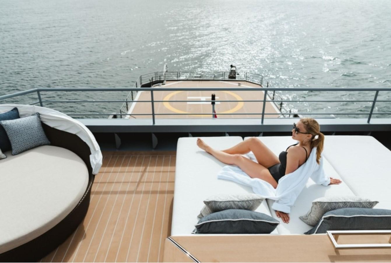 a woman lying on a deck aboard Q Yacht for Sale