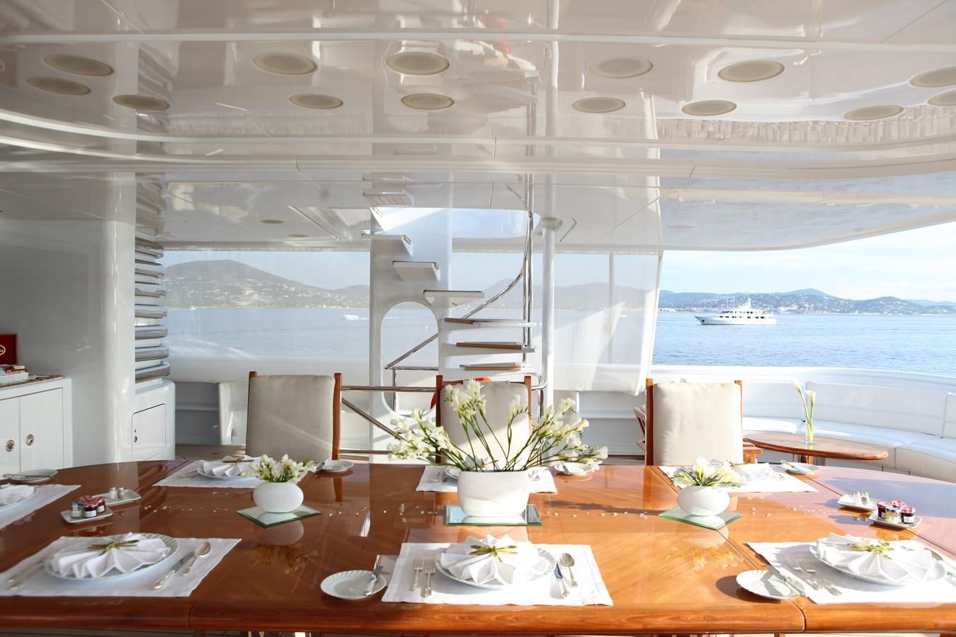 a table with plates and flowers aboard APOGEE Yacht for Sale