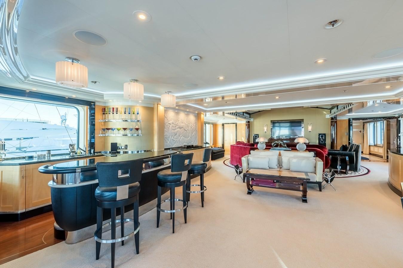 a large room with a bar and chairs and a table aboard MARGUERITE Yacht for Sale