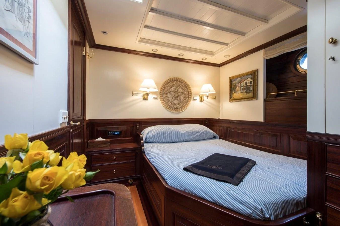 a bed with a blue sheet on it and a round pillow on the bed aboard SHENANDOAH OF SARK Yacht for Charter
