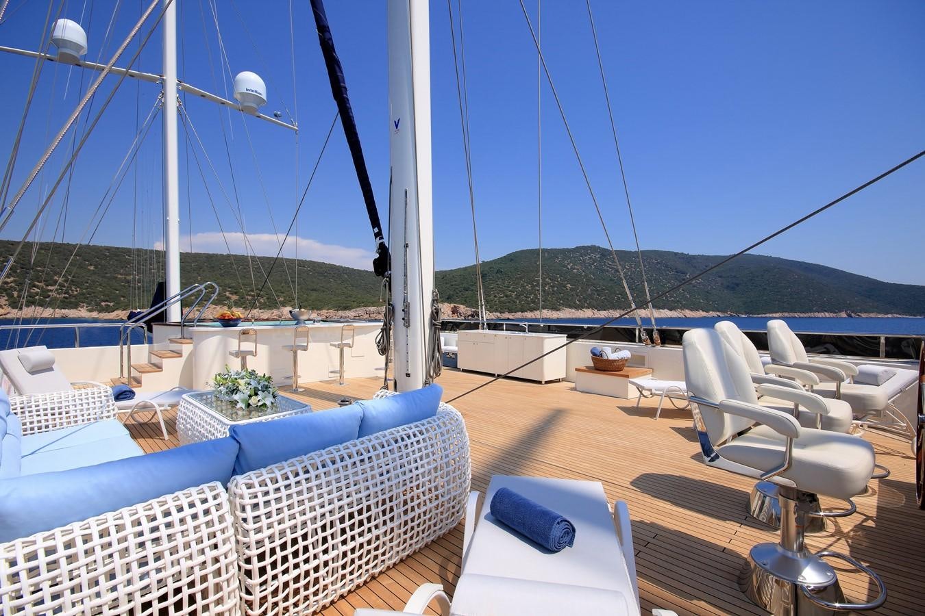 a deck with chairs and a table on it aboard MEIRA Yacht for Sale