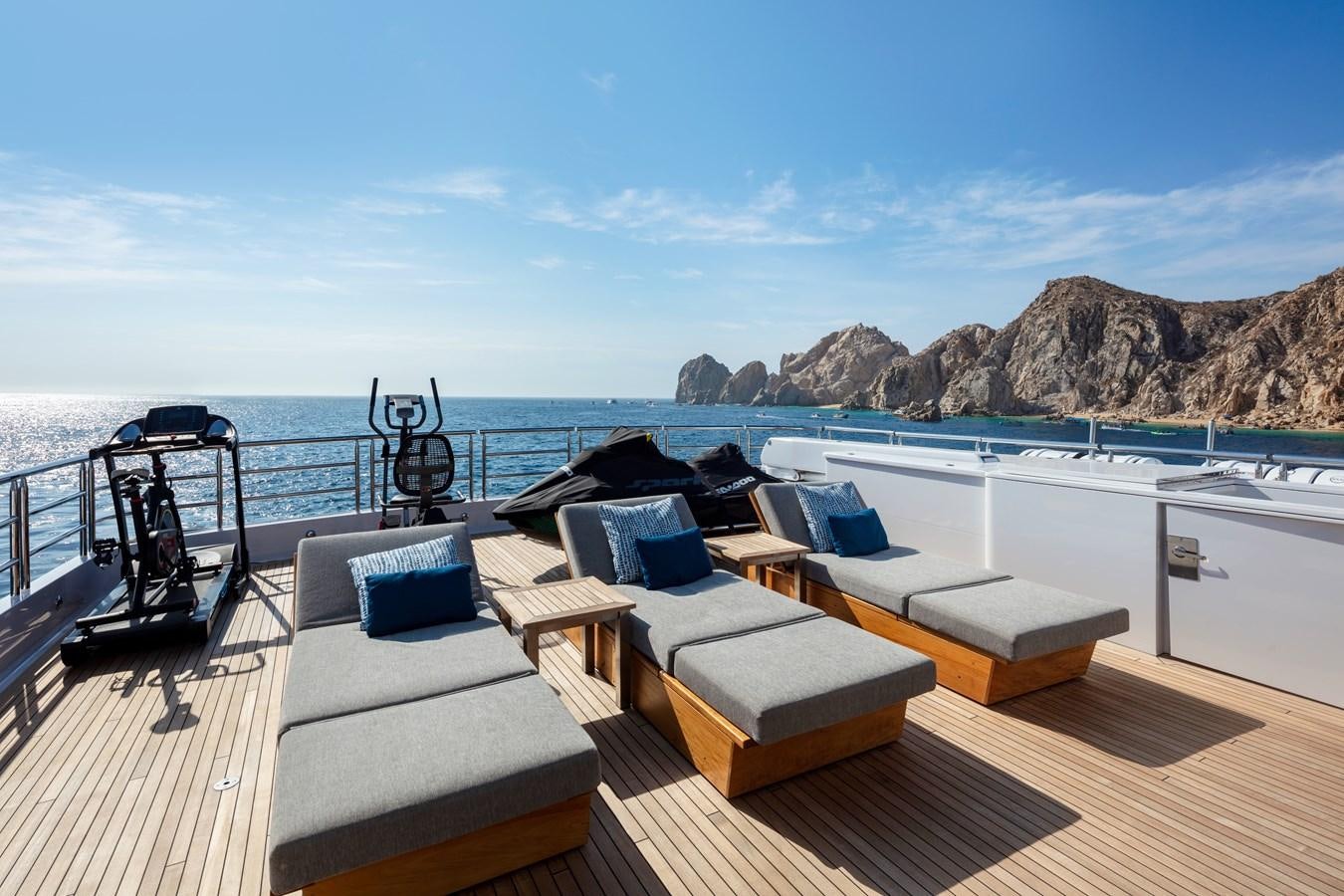a deck with a view of the ocean and mountains aboard CHAMPAGNE SEAS Yacht for Charter
