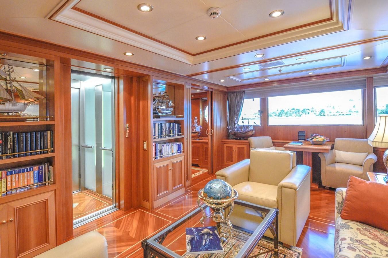 a living room with a glass coffee table and a bookcase aboard TE MANU Yacht for Sale
