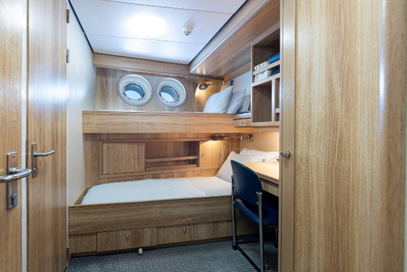 a room with a bed and a desk aboard VIBRANCE Yacht for Sale