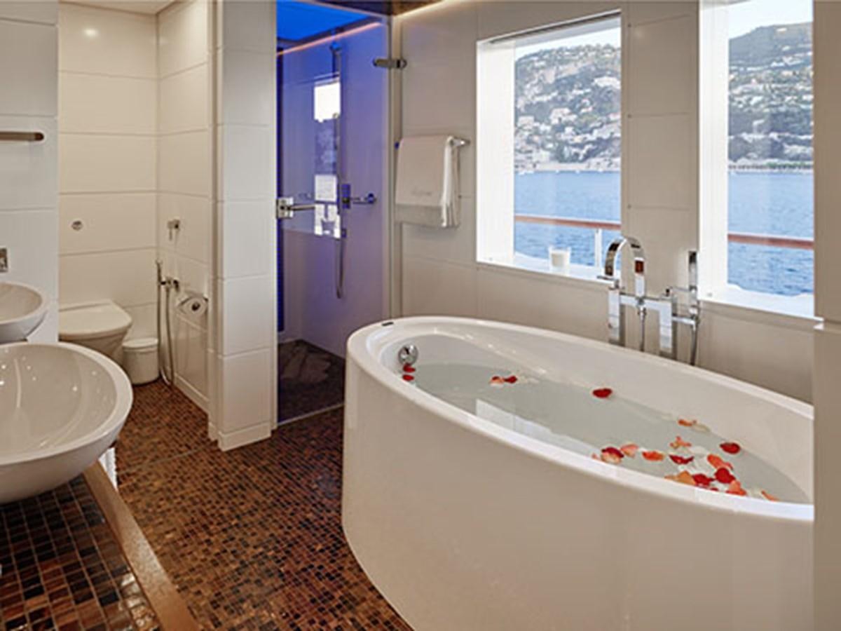 a bathroom with a tub sink and toilet aboard NASSIMA Yacht for Sale