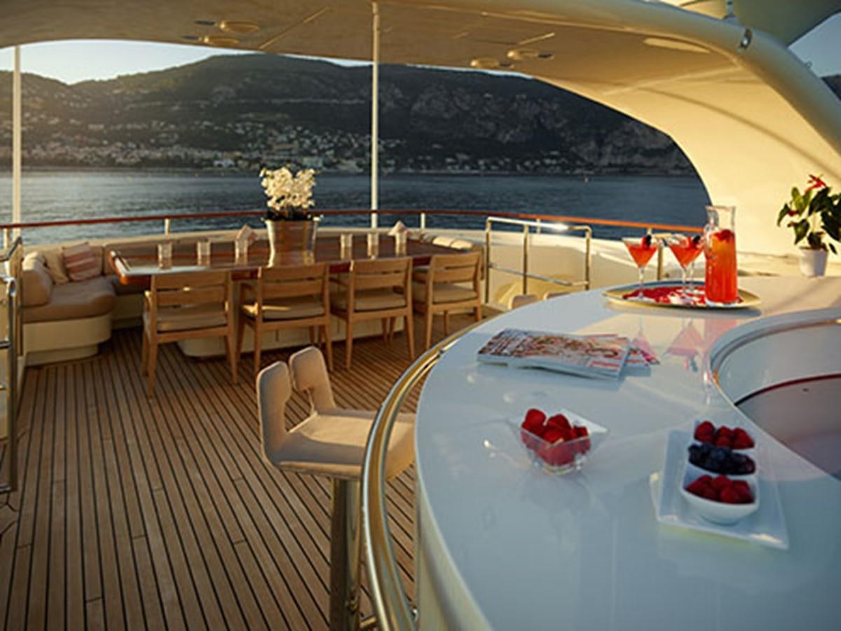 a table set for a meal on a deck overlooking a large body of water aboard NASSIMA Yacht for Sale
