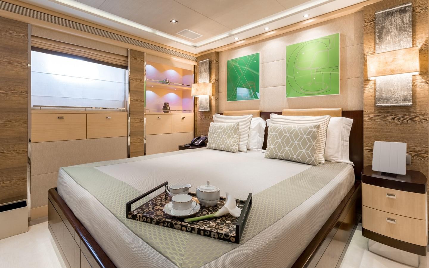 a bed with a white sheet and a table with a tray on it aboard ATINA Yacht for Sale