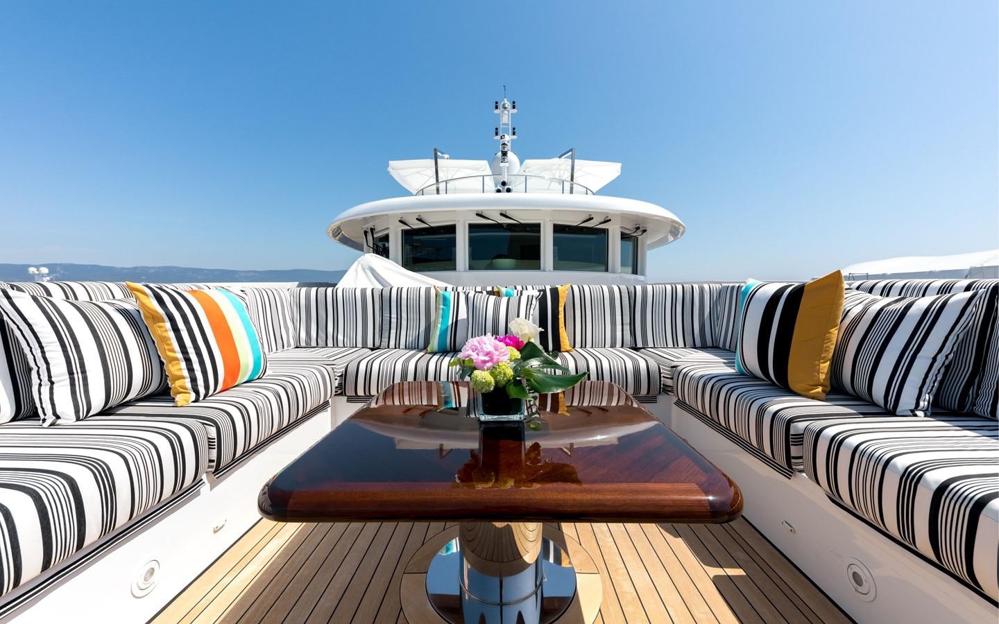a couch with a table and a vase of flowers on it aboard ATINA Yacht for Sale
