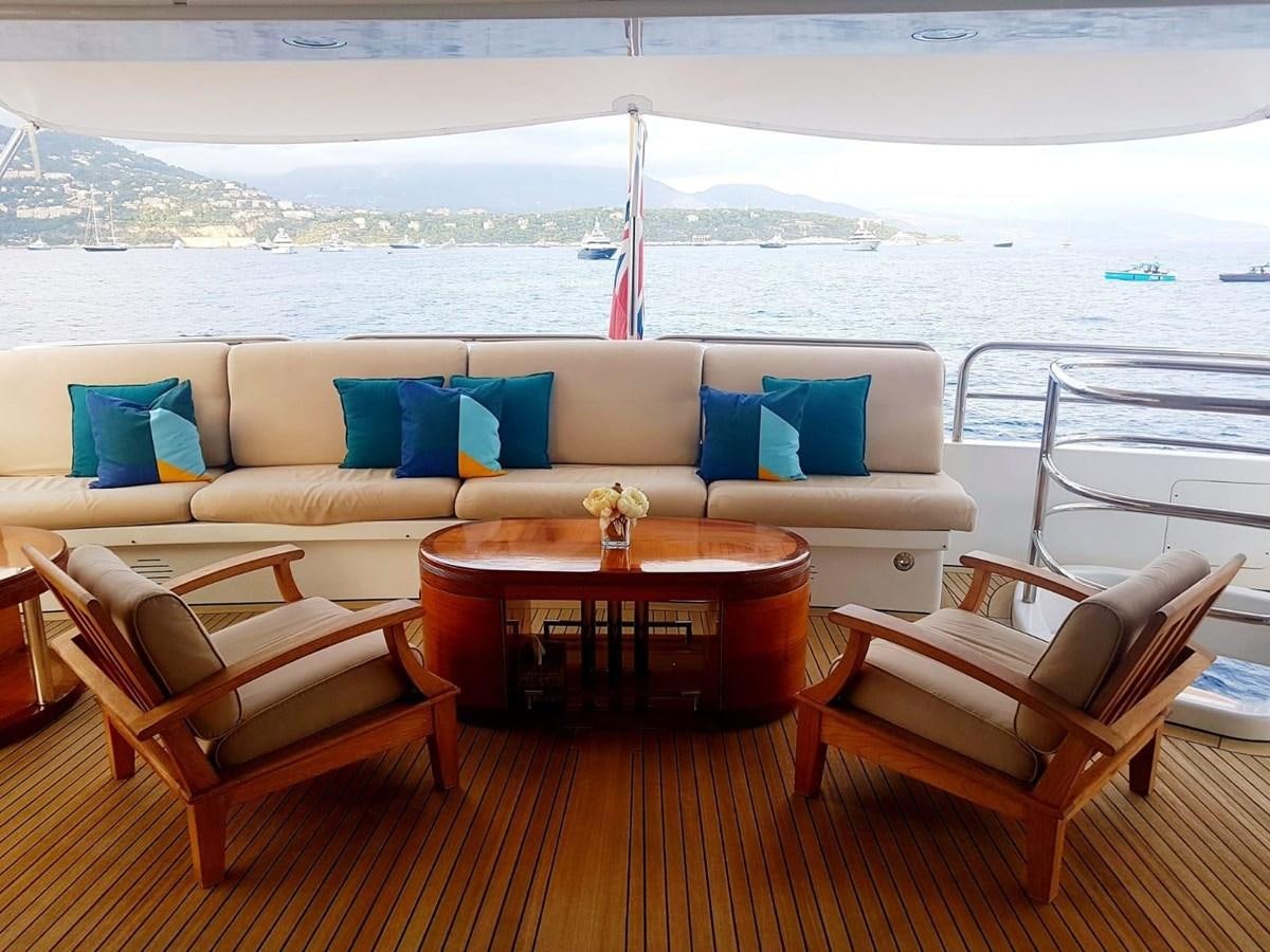 a couch and chairs on a deck overlooking a body of water aboard MORE Yacht for Sale