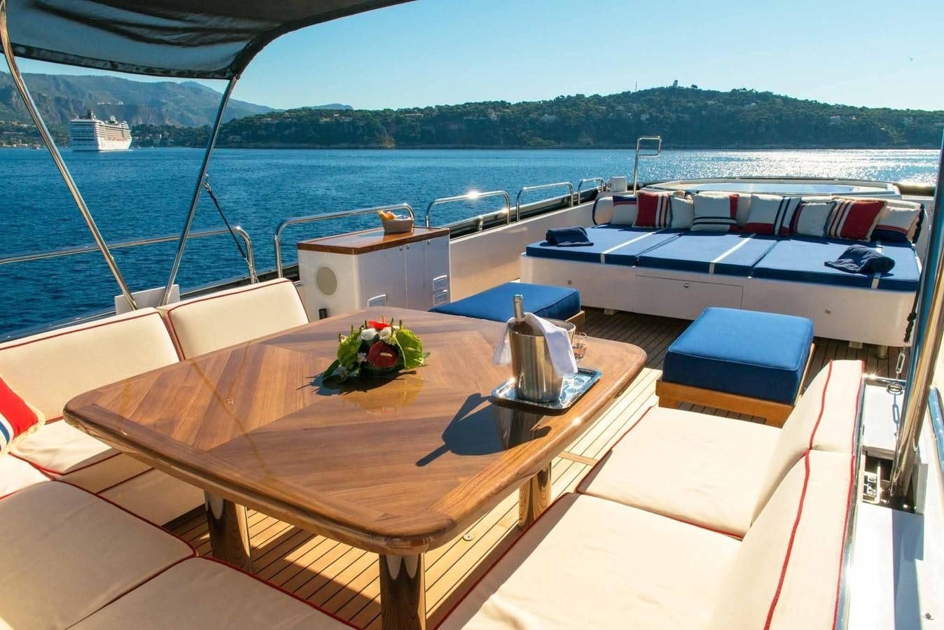a table with a flower on it next to a boat on a body of water aboard ELEMENT Yacht for Charter