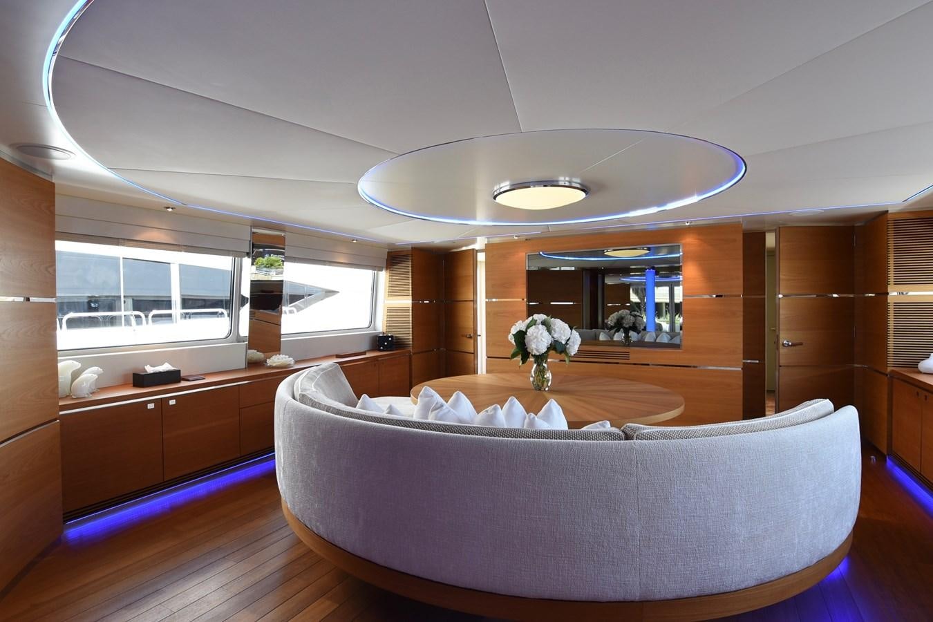 a large living room with a large white sofa and a large white chandelier aboard LIFE SAGA Yacht for Sale