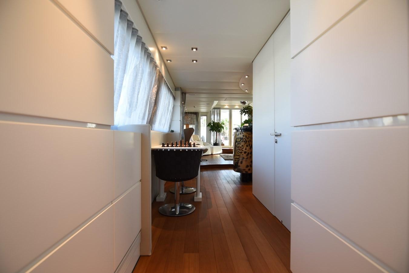 a room with a wood floor and a table with chairs and a window aboard LIFE SAGA Yacht for Sale