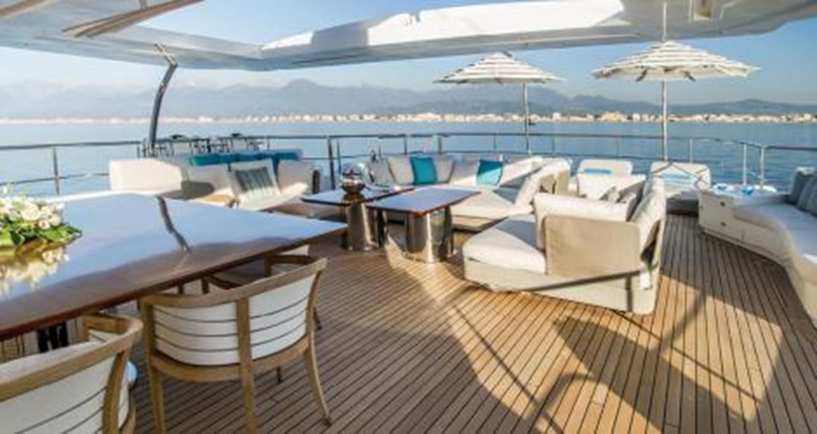 a deck with chairs and tables on it aboard NELA Yacht for Sale