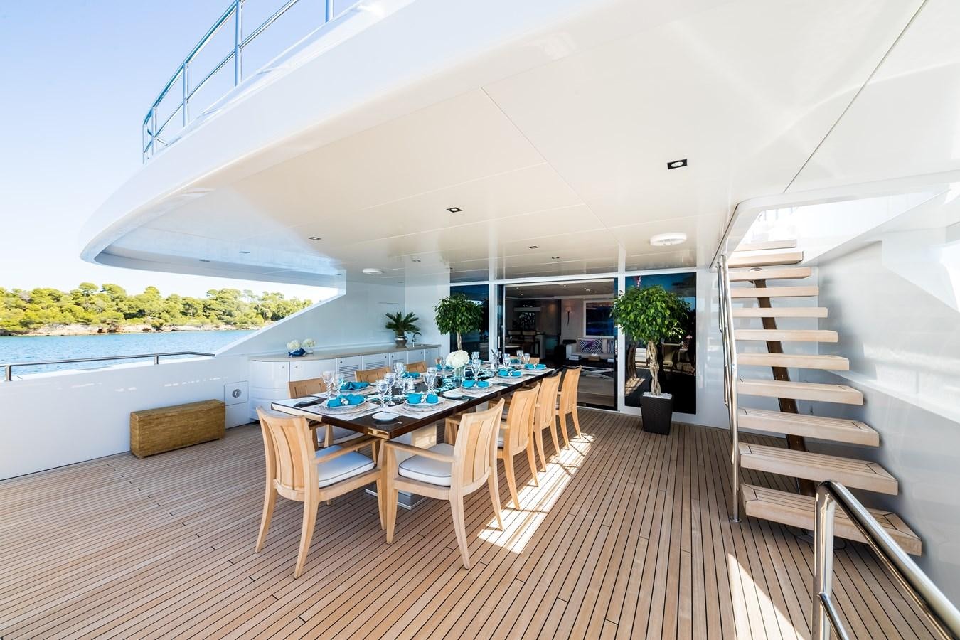 a long table and chairs in a room with a staircase and a white ceiling aboard TIMBUKTU Yacht for Sale