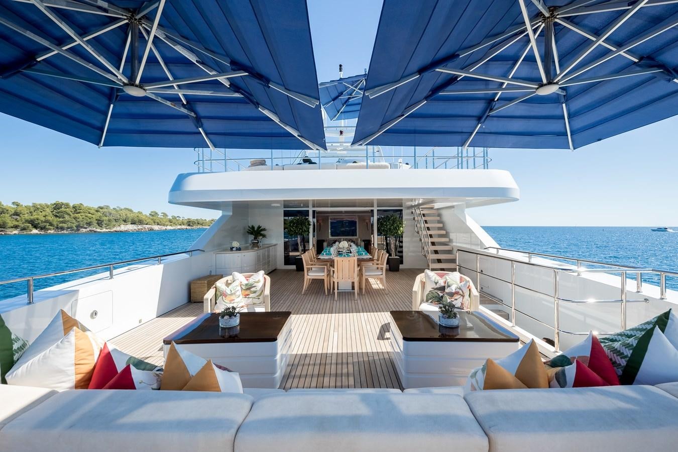 a lounge area on a deck overlooking a beach aboard TIMBUKTU Yacht for Sale
