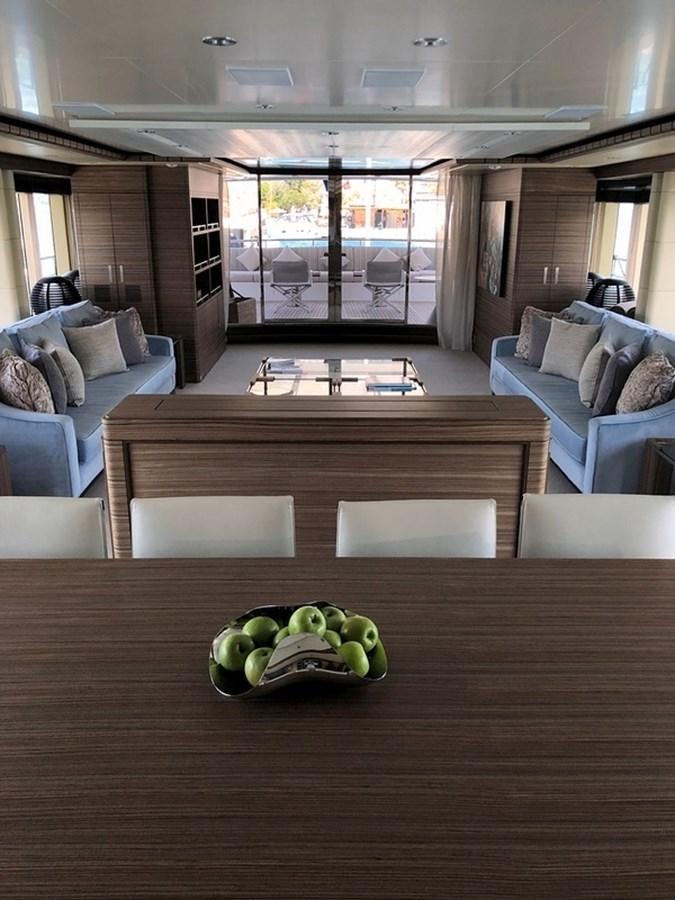 a room with a couch and a table with chairs and a window aboard ORYX Yacht for Sale